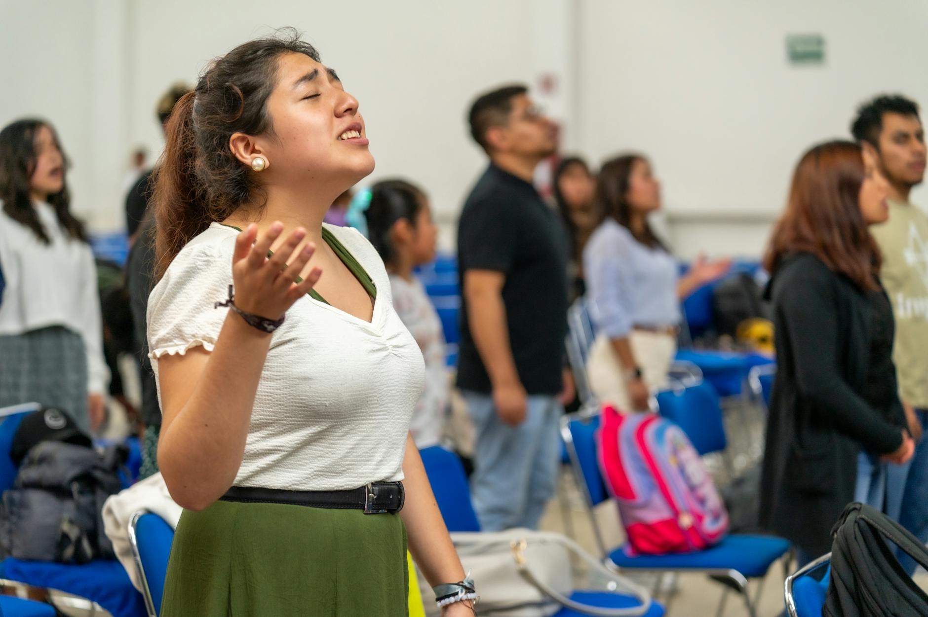 Młodzi dorośli modlący się we wspólnocie, unoszący ręce podczas uwielbienia